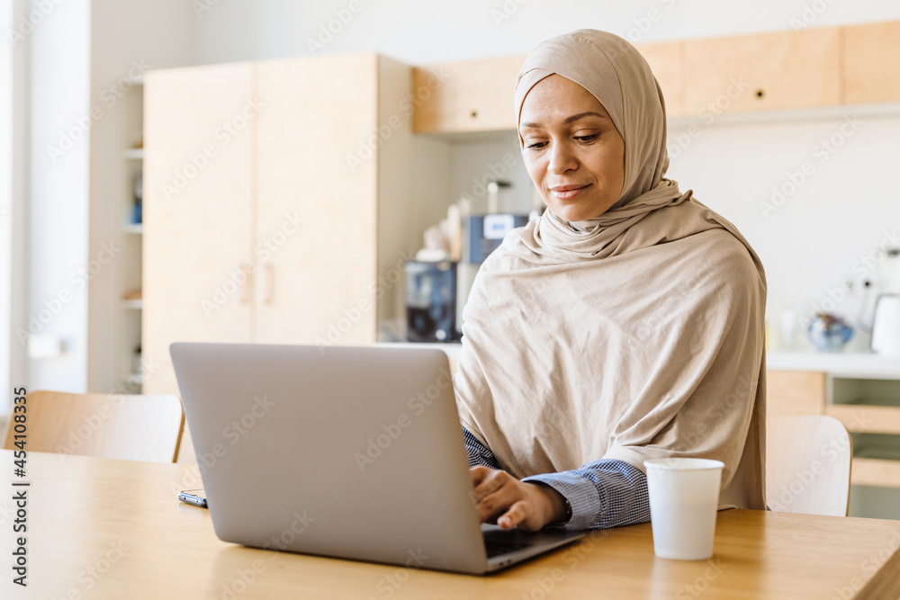 Middle eastern woman in hijab working with laptop at office kitchen Middle eastern woman in hijab working with laptop at office kitchen
