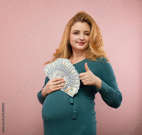 Young pregnant woman holds hundred dollar bills 