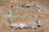 The inscription SOS made of small seashells on the sand in a rectangular garbage frame. Nature asks for help and protection from garbage pollution.