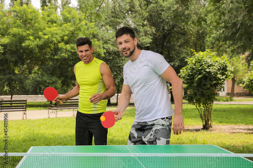 Men playing ping pong in park on summer day © New Africa