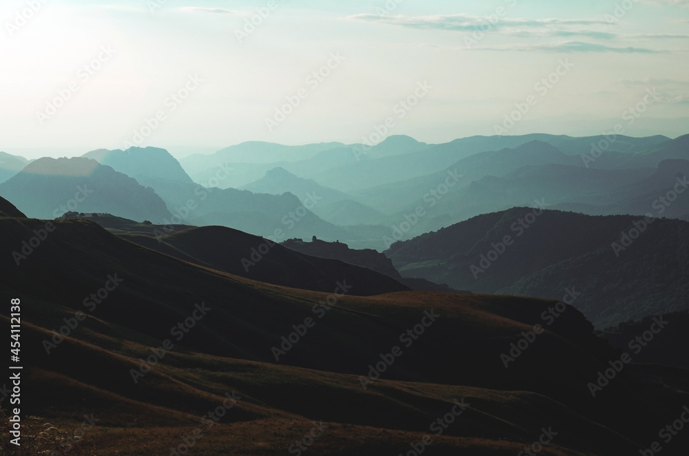 Beautiful panorama of green hills and mountains at sunset. Mountain pass and road.