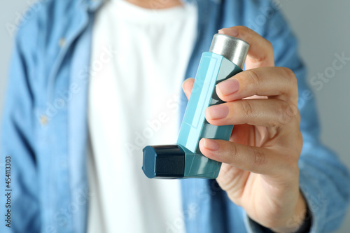 Young woman holds asthma inhaler, close up