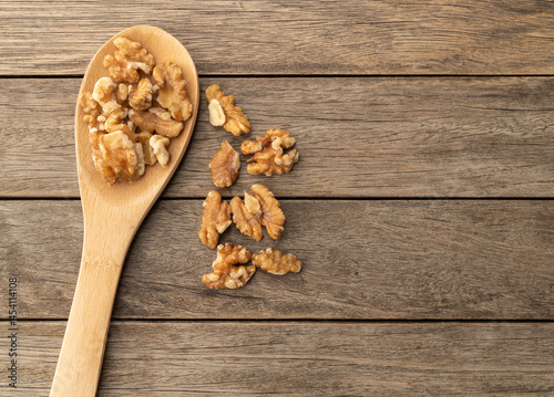 Walnuts in a spoon over wooden table with copy space