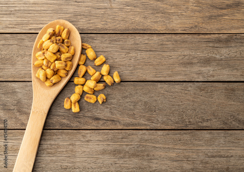 Fried corn in a spoon over wooden table with copy space