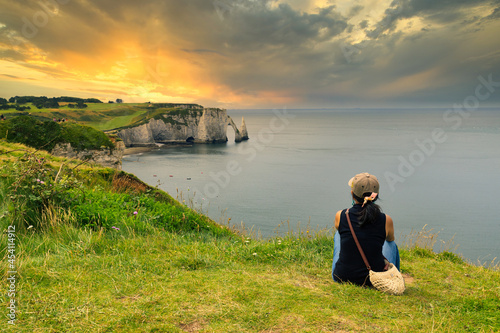 Woman contemplating sunset over the Etretat bay