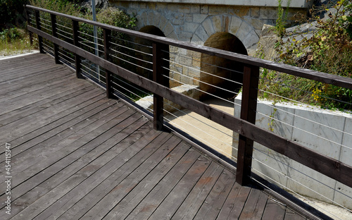 wooden bridge with a stone foundation newly built for cyclists over a stream by the pond. wooden beams connected by screws and rope stainless steel cable railings photo