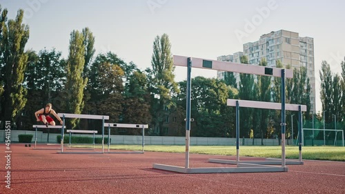 Low angle shot of a professional sportsman running a distance with obstacles. Young male athlete training in the stadium photo