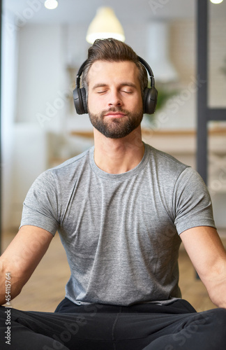 Handsome young man listening to music and meditating