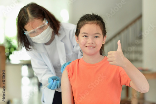 Asian child being vaccinated.Children vaccination by nurse.Medical doctor vaccinating school student in the arm.Paediatrician injecting vaccine to students in clinic.Girl thumb up.