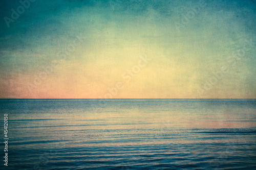 View from beach at sunset with ocean, colorful sky and sea with vintage grunge texture