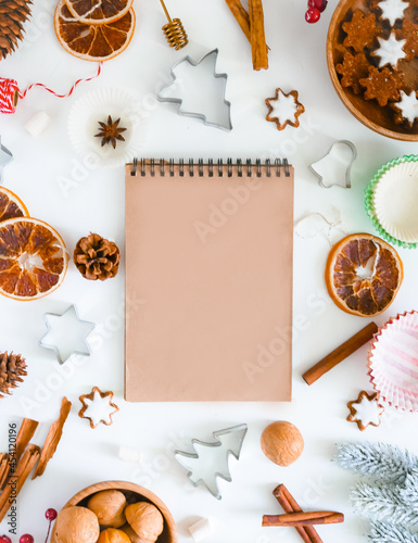 Christmas recipe background. Culinary background for a Christmas baking recipe. Notebook with dark sheets for writing a recipe, cookie molds, ingredients, spices,  top view, flat lay, copy space