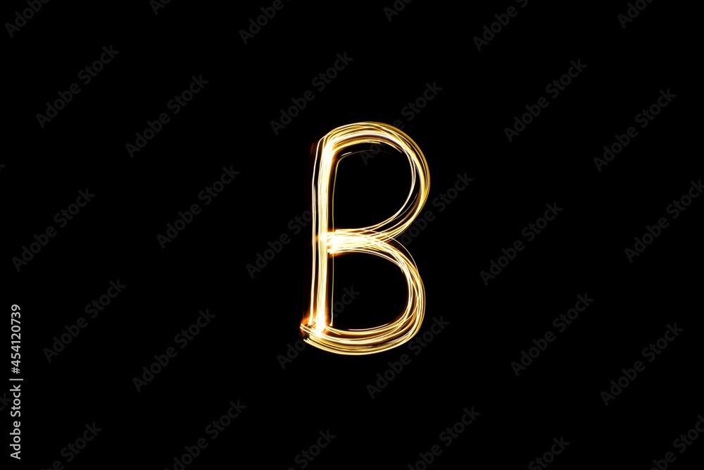 Obraz premium Drawn letter B with gold lights against black background. Light painting alphabet.