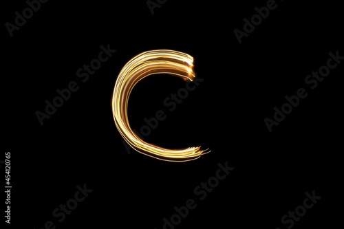 Drawn letter C with gold lights against black background. Light painting alphabet.