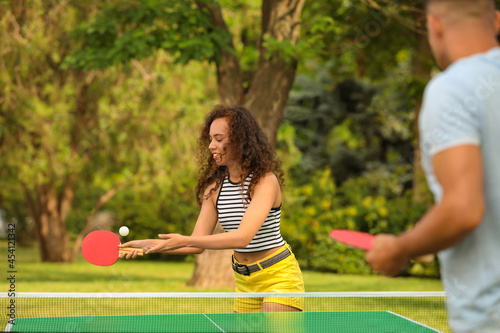 Friends playing ping pong outdoors on summer day © New Africa