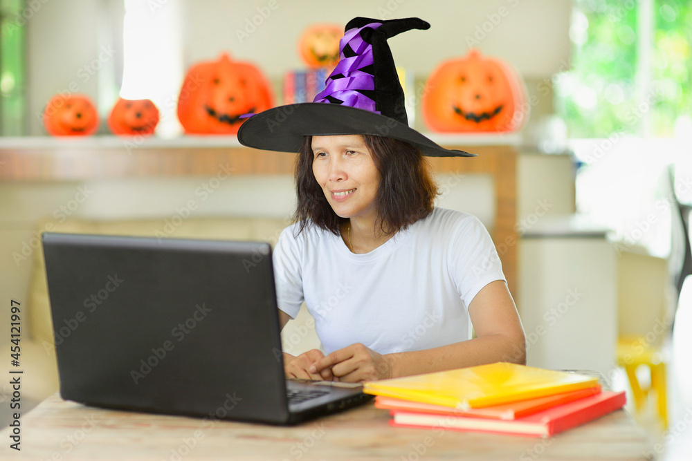 Asian primary teacher wearing witch hat teaching online in the fall ...
