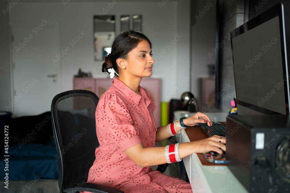 Young newlywed woman working from home on computer. Young newlywed woman working from home on computer.