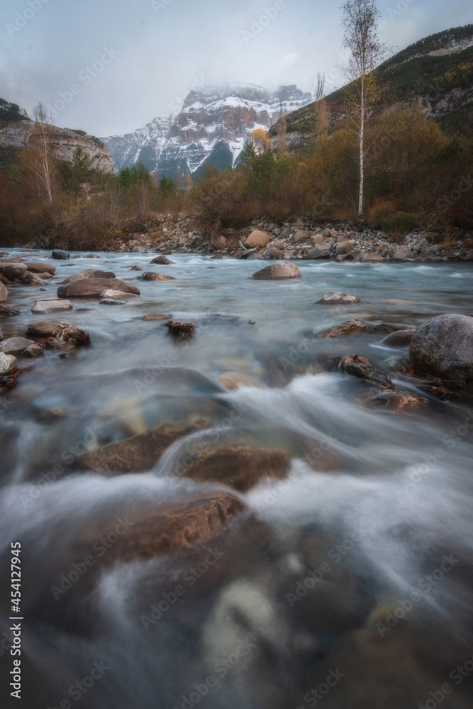 Vertical close view of a river in snowy winter mountain river landscape with trees in Ordesa Valley, Pyrenees, national park, Spain. Vertical close view of a river in snowy winter mountain river landscape with trees in Ordesa Valley, Pyrenees, national park, Spain.