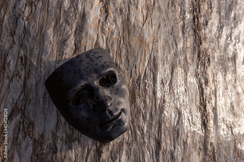 Selective focus black plastic mask placed on a beautifully patterned stone. give a strong feeling and has dark powers concept of the dark side of man There is space for text.