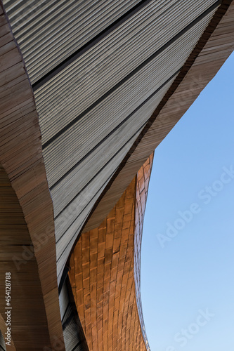 Low angle view, close-up, brown arched contemporary building exterior structure, abstract shape, distorted curves, a tourist attraction in a province of Thailand.