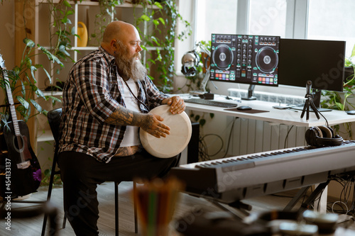 Positine obese man plays drum sitting in home audio record studio photo