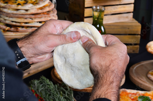 Pizza maker's hands kneading the dough. The cook makes pizza.