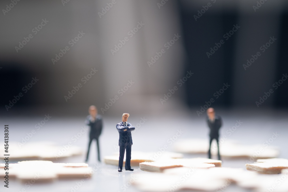 Miniature businessman standing in the center of the jigsaw puzzle piece Miniature businessman standing in the center of the jigsaw puzzle piece