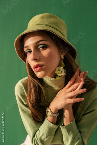Fashion portrait of elegant woman with green eyes makeup, wearing trendy green bucket hat, turtleneck sweater. Total color look, outfit