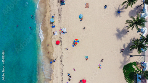 An aerial shot of tourists sunbathing on the sand and swimming in the ocean. Original public domain image from Wikimedia Commons