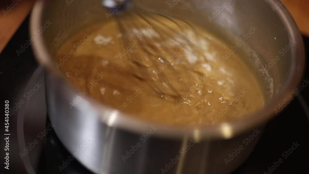 Professional female confectioner is making cream for cake. Female is cooking in kitchen. Process of making clear glaze at home. Culinary, baking concept Professional female confectioner is making cream for cake. Female is cooking in kitchen. Process of making clear glaze at home. Culinary, baking concept