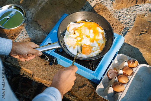 Person cooking omelette in fying pan on campin stove photo