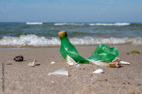 Garbage on the beach. Plastic on the beach. Pollution of the coast with plastic bottles. Green empty bottle.