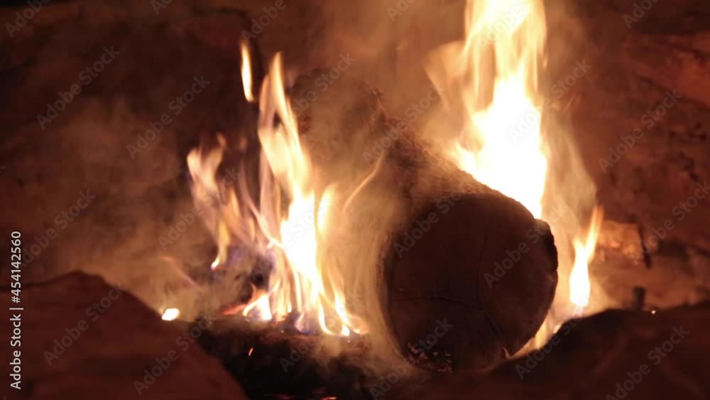 Firepit log burning on fire in a bonfire with orange flames