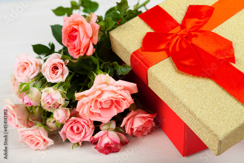 Bouquet of pink roses in a red box on a wooden background.