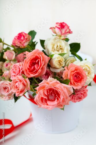 Bouquet of pink roses in a vase with a ribbon on a wooden background.