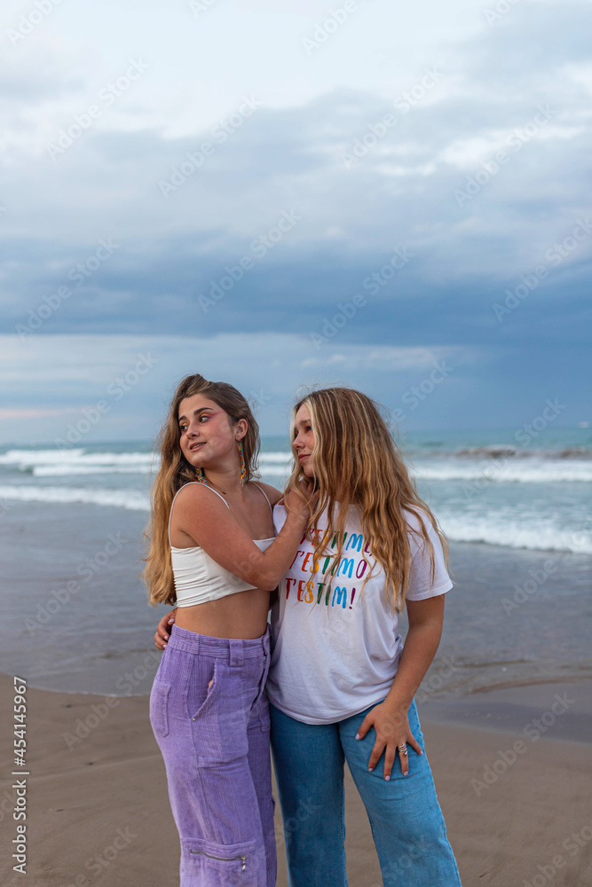 Young lesbian women embracing on beach in evening