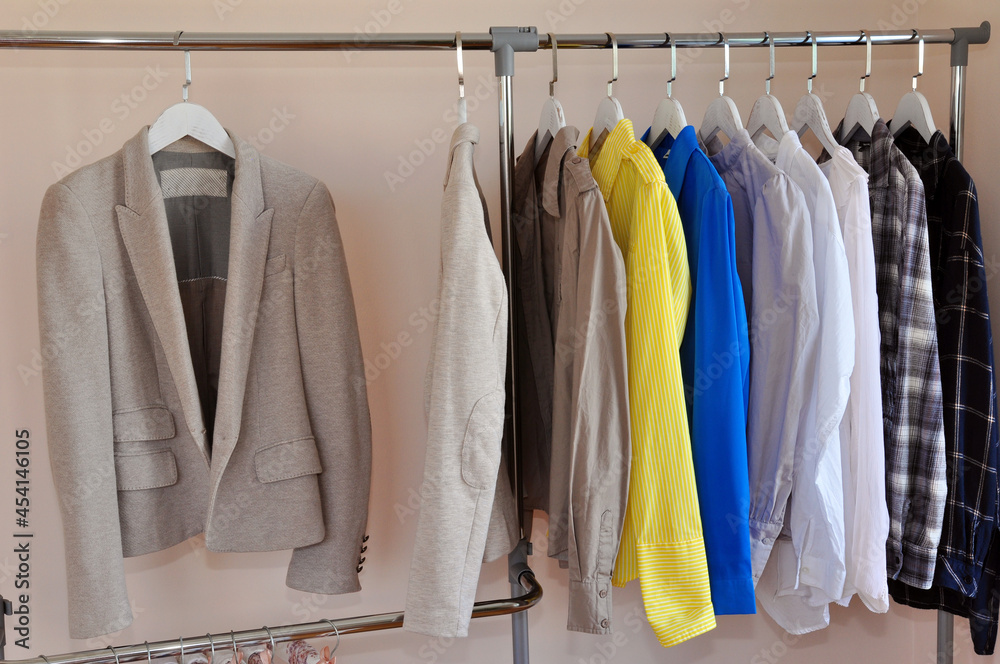 Rack with business clothes after dry cleaning near light wall
