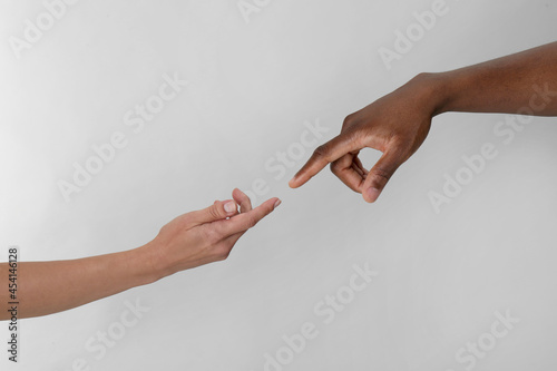 Slika na platnu Woman and African American man touching fingers on light grey background, closeu