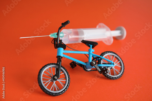 Bike model and syringe on red background. Using doping in cycling sport concept photo