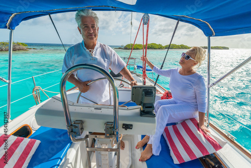 Senior couple enjoying sailing trip on a luxury summer holiday vacation, sunny weather and ocean in background, love and romance on a beautiful yacht
