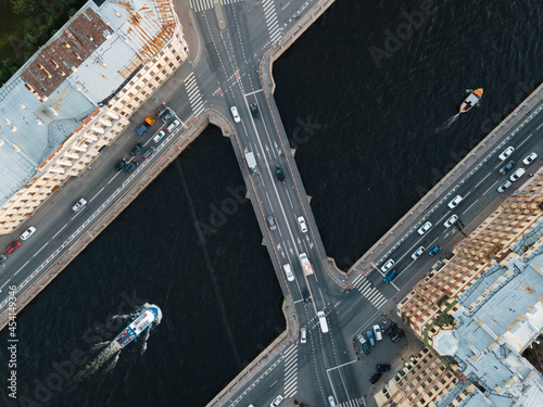 View from above on Ismaylovsky bridge across Fontanka river. Blurred car motion on bridge. A pleasure boat is floating on the water. Close up view from above. Historical center of St Petersburg.