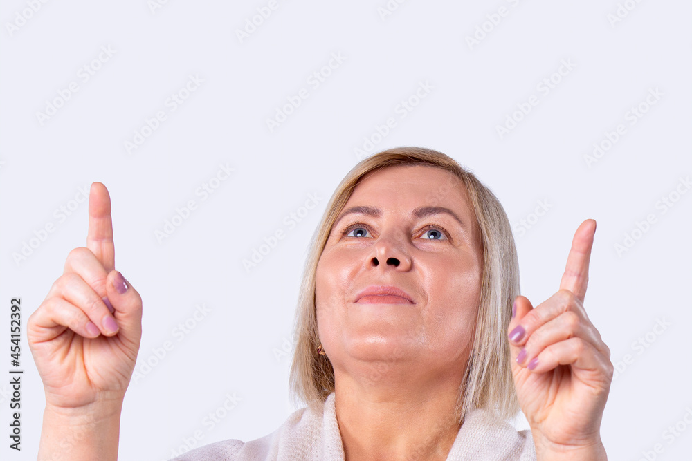 Close up photo of an attractive blonde woman looking up holding two index fingers up with pink manicure. Close up photo of an attractive blonde woman looking up holding two index fingers up with pink manicure.