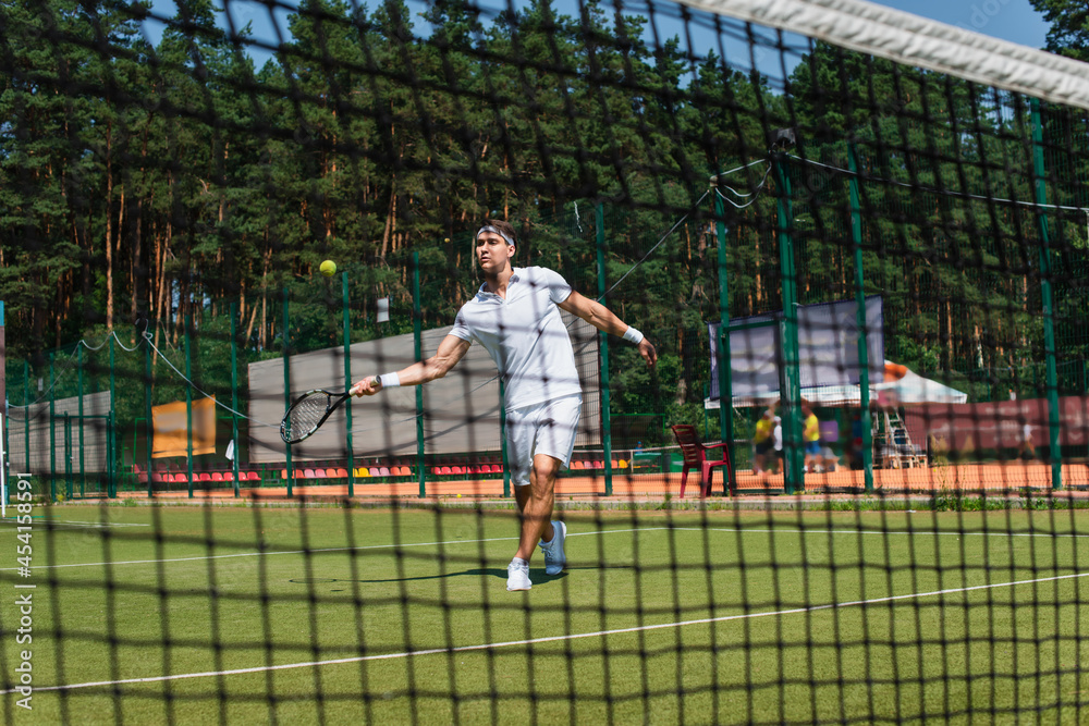 Sportsman playing tennis on court near blurred net Sportsman playing tennis on court near blurred net