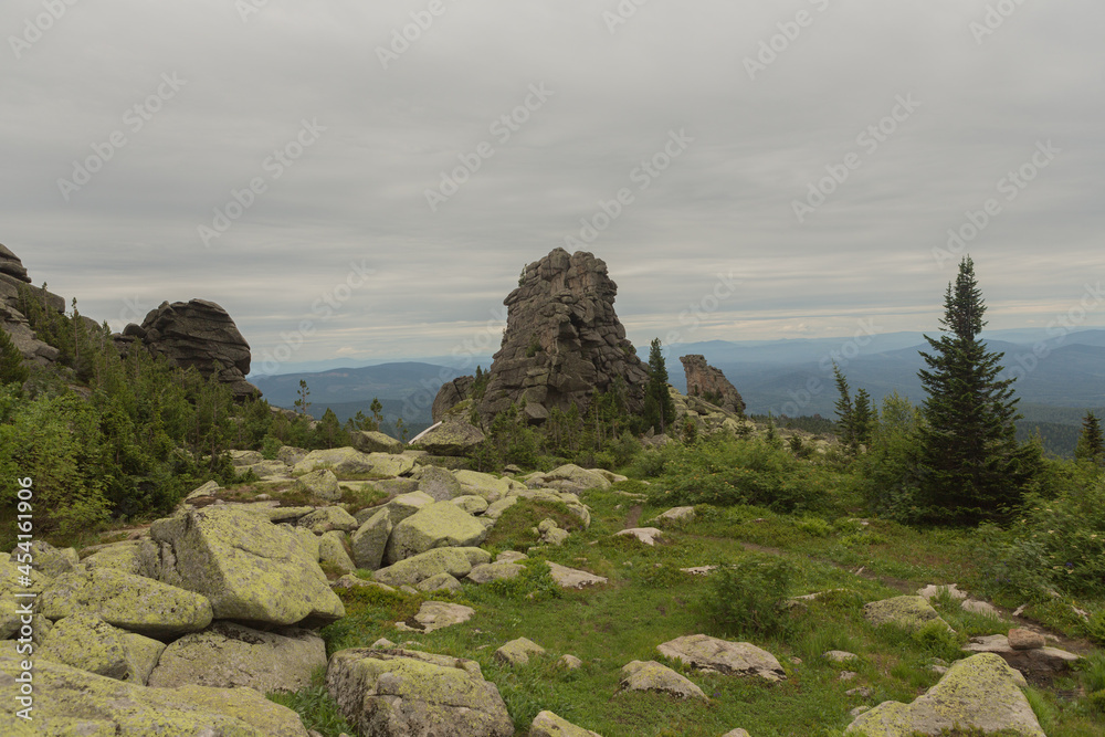 large kurum stones lie in the forest in the mountains, stones covered with moss, against the background of the forest, mountain landscape, high in the mountains.