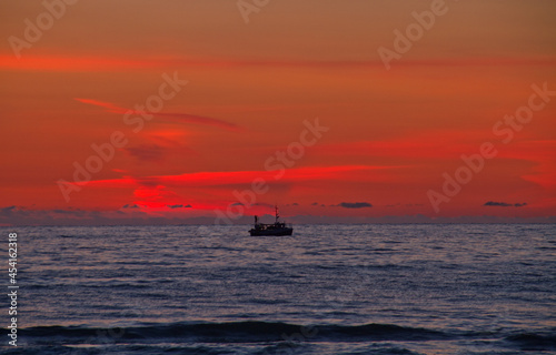 Silhouette of fishing boat on calm sea just after sunset © Matauw