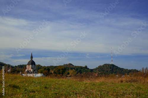 outskirts meadow with church building and TV tower on background, old and new construction concept picture with empty copy space for text on calm sky space