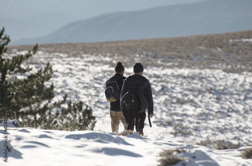 two man with backpack walking through a snowy high mountain landscape, he is above the clouds