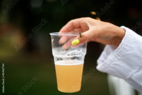Wasp sits on a woman's hand holding a glass with a drink