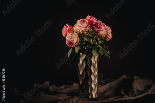 Dry and dead roses in an elegant vase on a black background