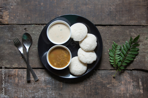 Popular South Indian snacks idli sambar or idly sambhar prepared by steaming fermented rice and served with coconut dip and vegetable soup. Top view. photo