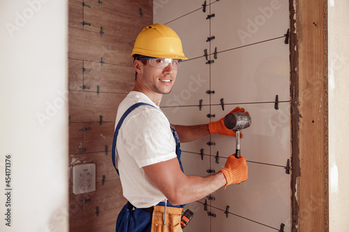 Joyful male builder installing ceramic wall tile in house